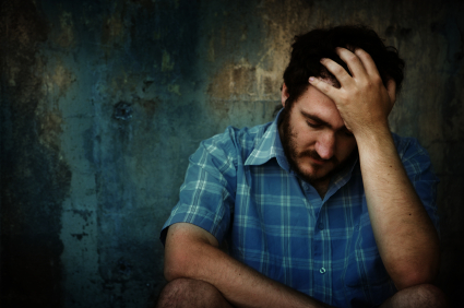 man with depression sitting down holding his head up